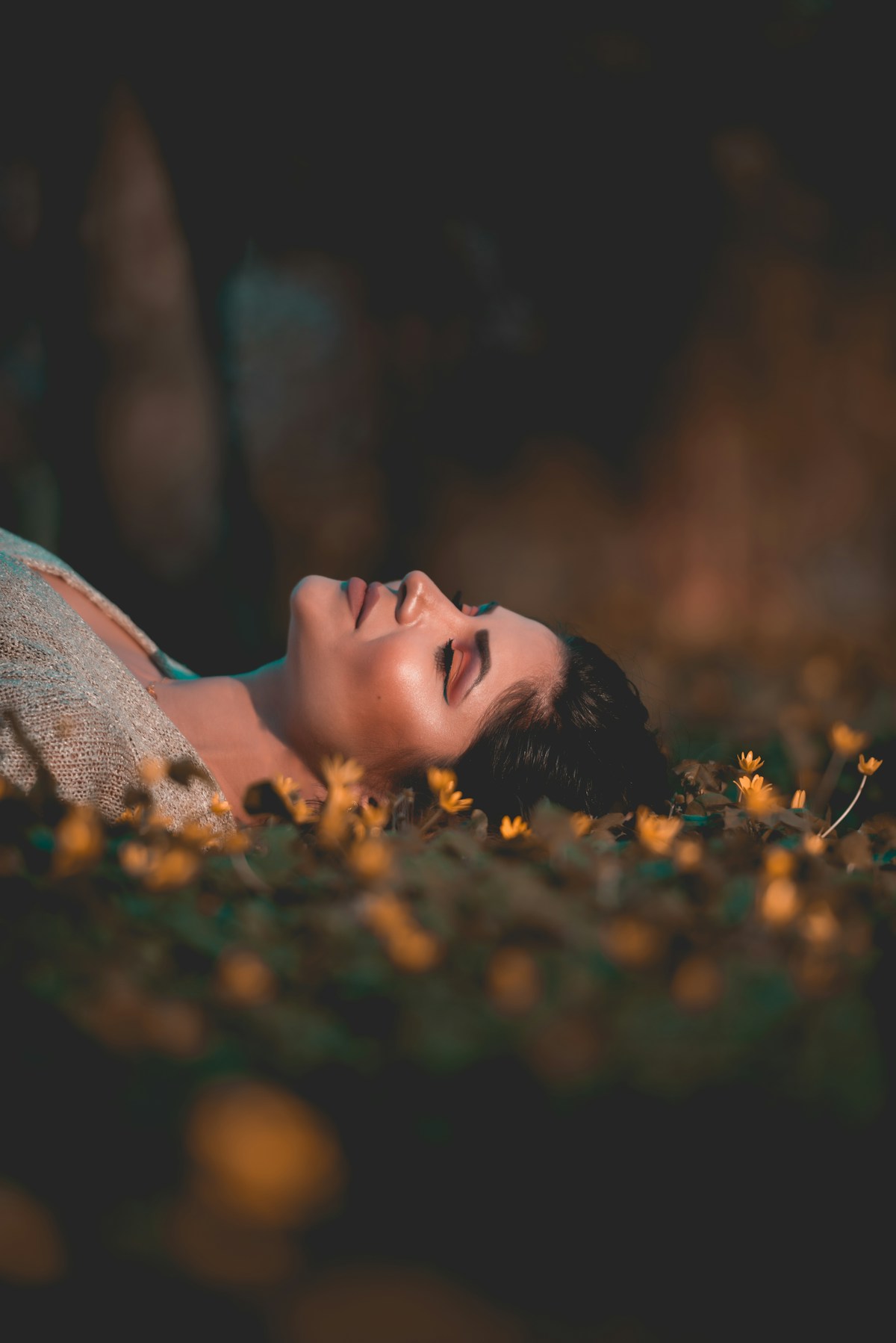 Mulher deitada num campo de flores ao entardecer; imagem ilustrativa